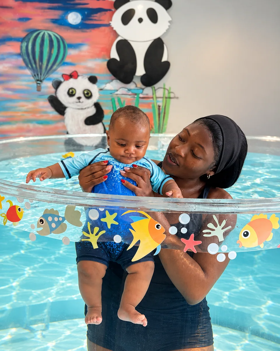 An adult supporting a little one in Floating Panda’s round pool